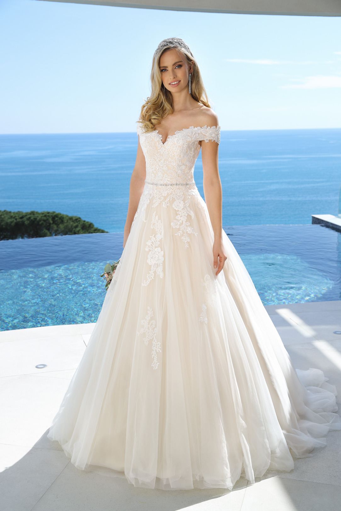 A-Linie Hochzeitskleid von Ladybird Modell 421023. Das schulterfreie A-Linie Brautkleid ist mit  feinsten Spitzenapplikationen am Oberteil und Rock besetzt. Der dekorative Carmenausschnitt und der weite Organzarock setzt deine Figur toll in Szene